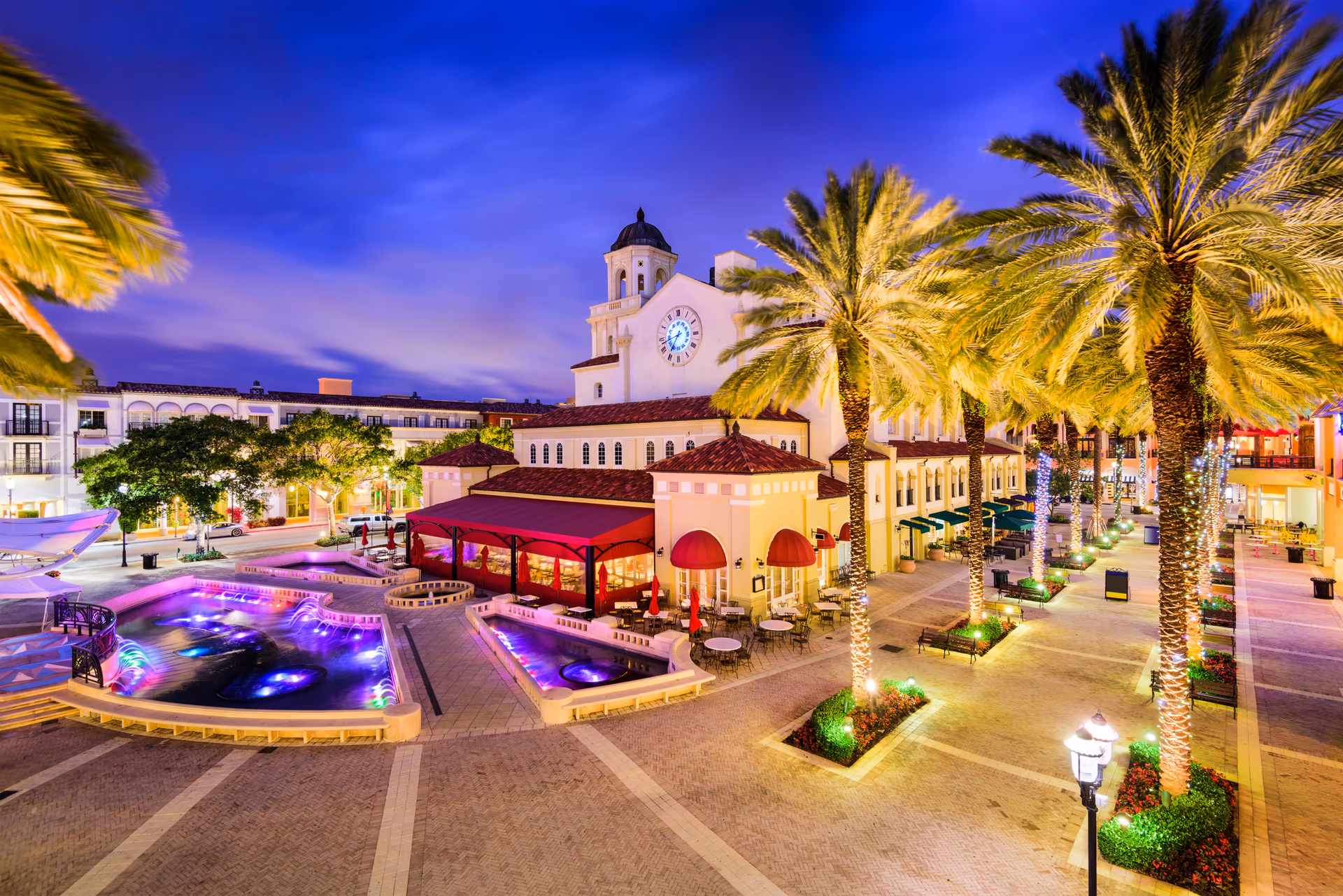 Rosemary Square plaza in downtown West Palm Beach at blue hour with illuminated fountains and Mediterranean revival architecture